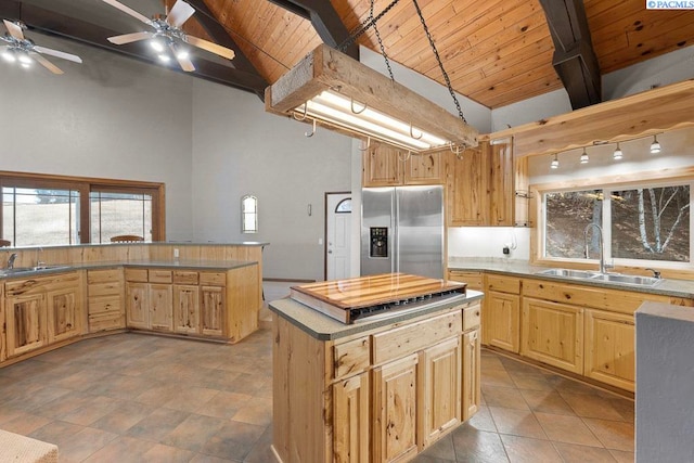 kitchen with appliances with stainless steel finishes, beam ceiling, a sink, and light brown cabinetry