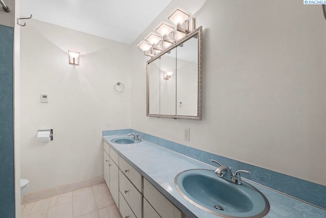 full bathroom with double vanity, a sink, toilet, and baseboards