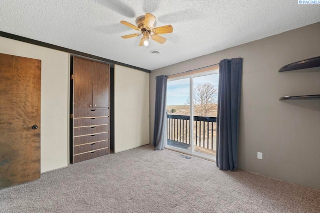 unfurnished bedroom featuring access to exterior, carpet, ceiling fan, and a textured ceiling