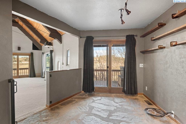 unfurnished room featuring vaulted ceiling with beams, a textured ceiling, visible vents, and a wealth of natural light