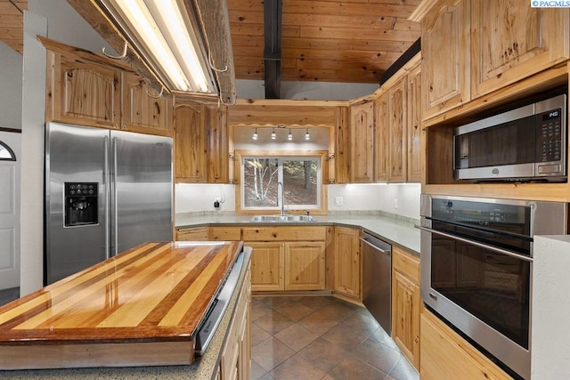 kitchen with appliances with stainless steel finishes, light brown cabinets, a sink, wood counters, and dark tile patterned floors