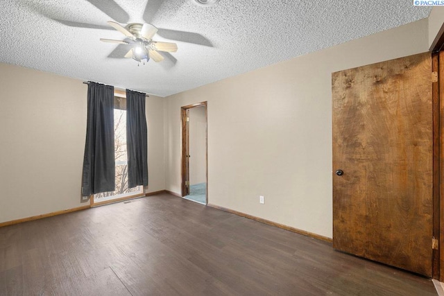 spare room featuring a textured ceiling, wood finished floors, and baseboards