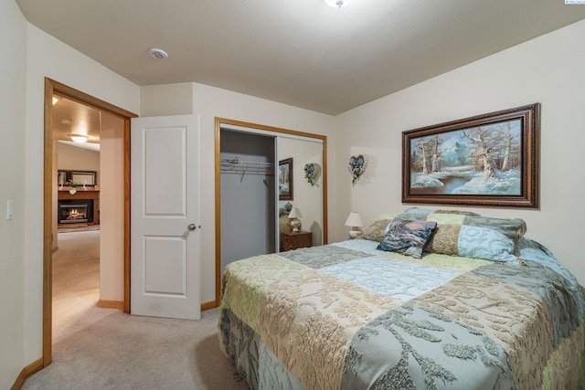 704 W 18th Ct, Kennewick, WA 99337 - bedroom with light carpet, a closet, baseboards, and a warm lit fireplace
