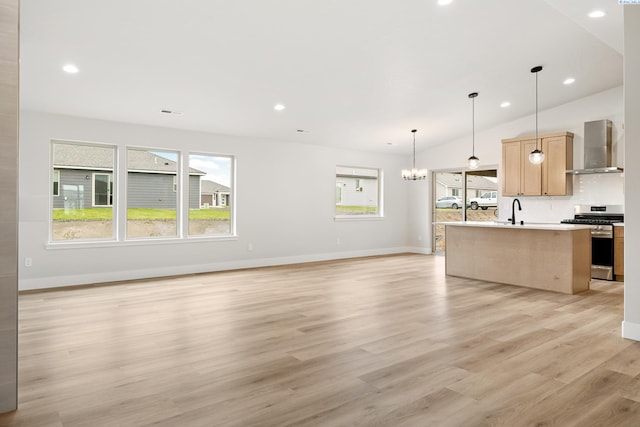10709 Kokanee Dr, Pasco, WA 99301 - kitchen featuring stainless steel gas range oven, wall chimney exhaust hood, open floor plan, light countertops, and a kitchen island with sink