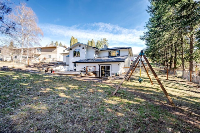 rear view of property with a fenced backyard, a deck, a playground, and a yard