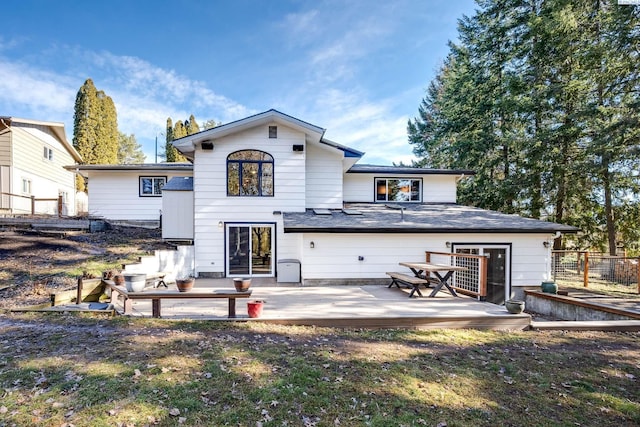 rear view of property with fence, a deck, and a lawn