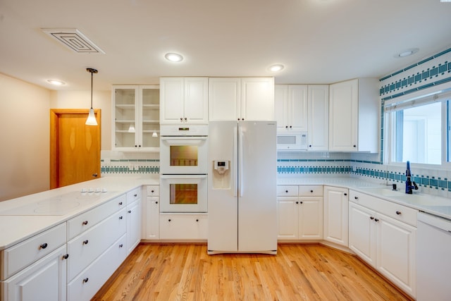 kitchen with light countertops, visible vents, a sink, light wood-type flooring, and white appliances