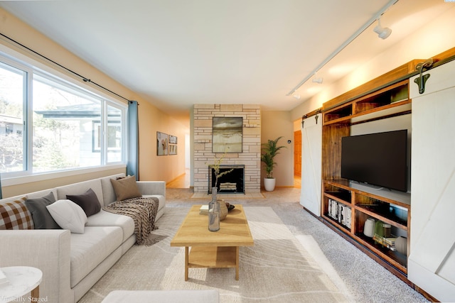 living room with rail lighting, a fireplace, and light colored carpet