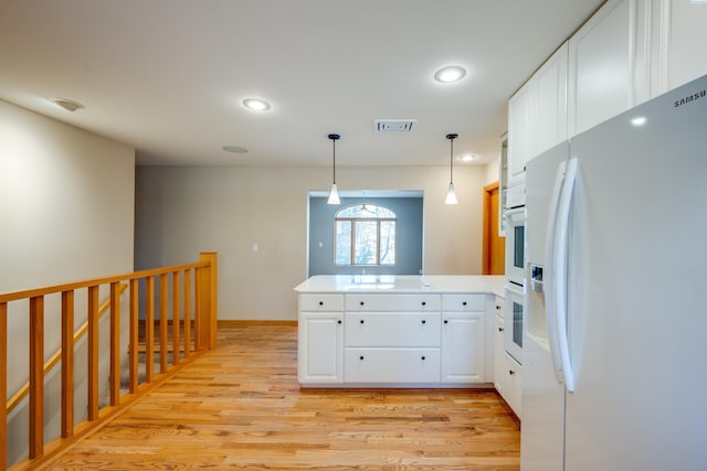 kitchen with visible vents, light wood-style floors, white cabinetry, white appliances, and a peninsula