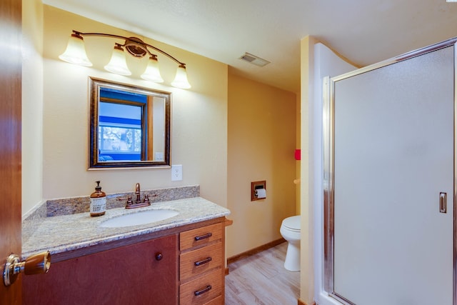 full bath with visible vents, toilet, vanity, a shower stall, and wood finished floors