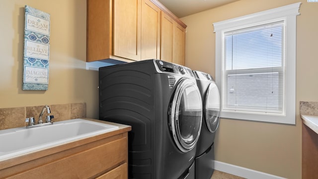 laundry area featuring washer and dryer, baseboards, cabinet space, and a sink