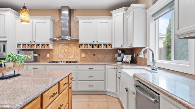 kitchen with light tile patterned floors, a sink, decorative backsplash, stainless steel appliances, and wall chimney exhaust hood