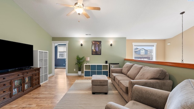 living room featuring baseboards, ceiling fan, vaulted ceiling, and light wood finished floors