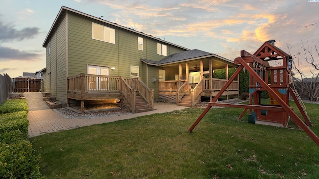 back of property with a yard, a deck, a fenced backyard, and a playground