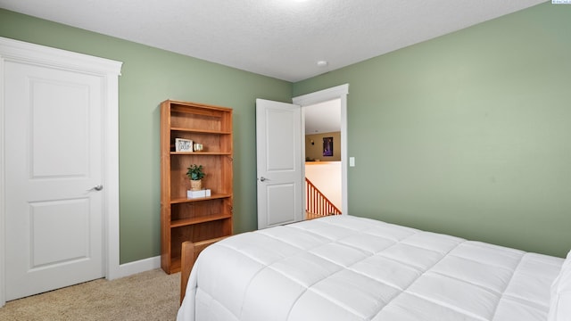 bedroom with baseboards, light carpet, and a textured ceiling