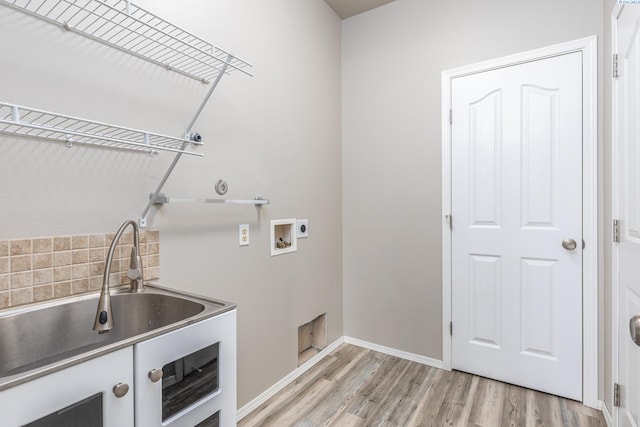 washroom with laundry area, baseboards, light wood-style floors, washer hookup, and a sink