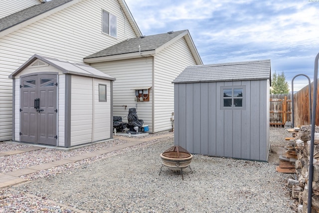 rear view of property featuring an outbuilding, a fire pit, and a shed