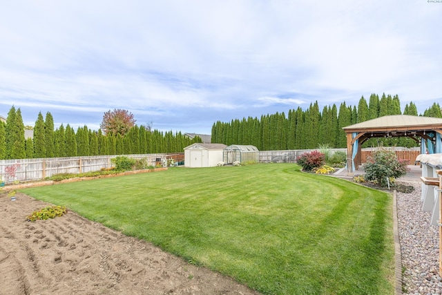 view of yard featuring a fenced backyard, an outdoor structure, a gazebo, and a storage shed