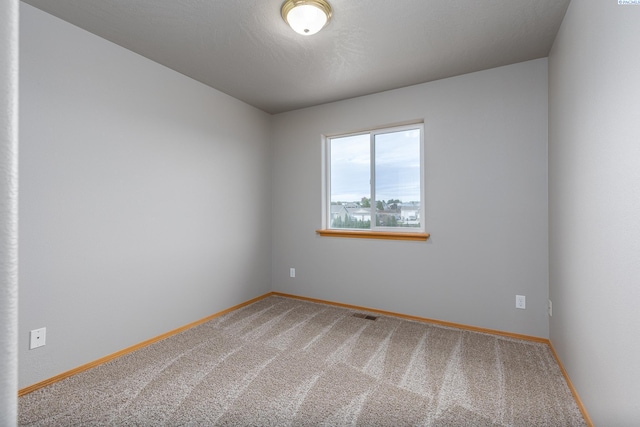 unfurnished room featuring carpet, visible vents, and baseboards