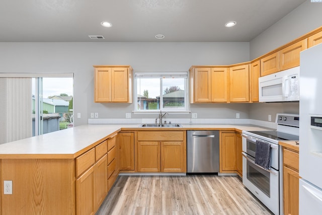 kitchen featuring a peninsula, white appliances, a sink, visible vents, and light countertops