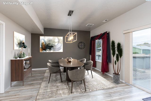 dining space with light wood finished floors, visible vents, and baseboards