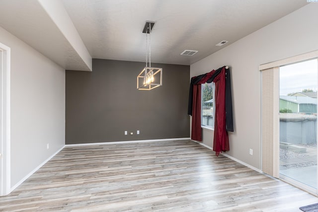 empty room featuring light wood-type flooring, baseboards, and visible vents