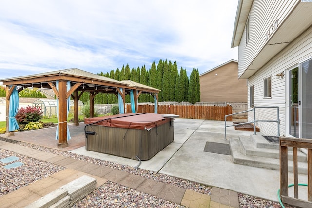 view of patio / terrace with a hot tub, a fenced backyard, and a gazebo