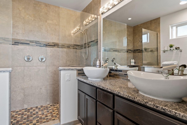 bathroom featuring vanity, a tile shower, and tile walls