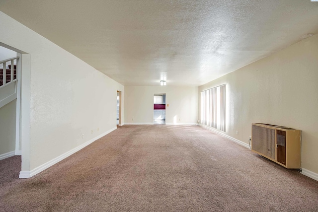 carpeted spare room with heating unit and a textured ceiling