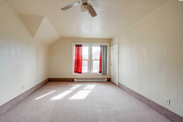 additional living space with vaulted ceiling, carpet floors, a textured ceiling, and a baseboard heating unit