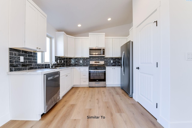 1610 Diamond Ave, Grandview, WA 98930 - kitchen featuring appliances with stainless steel finishes, light wood-style flooring, tasteful backsplash, white cabinets, and lofted ceiling