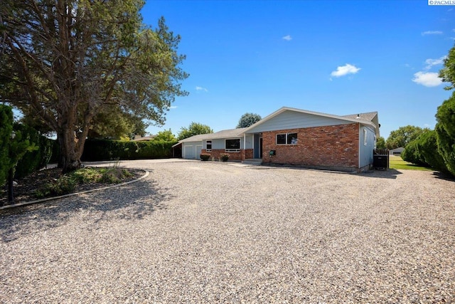 10012 Maple Dr, Pasco, WA 99301 - back of house with gravel driveway, brick siding, an attached garage, and central AC unit