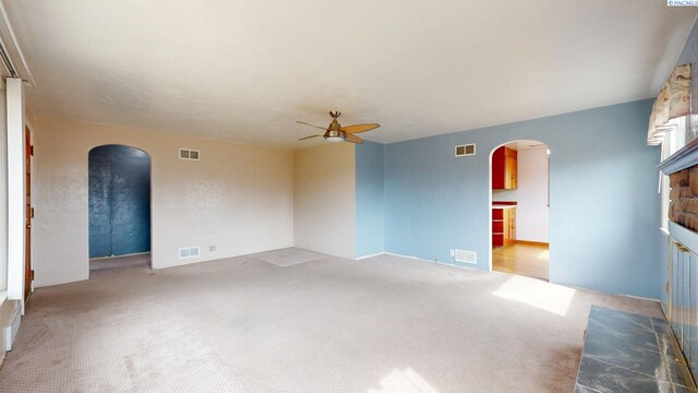 703 W Octave St, Pasco, WA 99301 - carpeted empty room featuring arched walkways, ceiling fan, and a fireplace with raised hearth