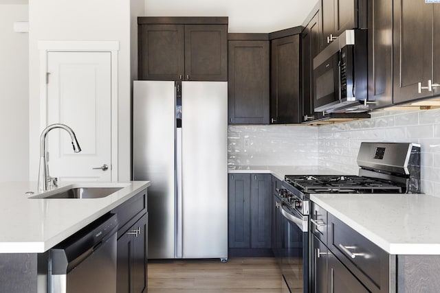6563 W 30th Pl, Kennewick, WA 99338 - kitchen featuring a sink, decorative backsplash, dark brown cabinets, appliances with stainless steel finishes, and light wood-type flooring