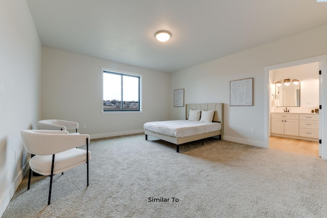 bedroom featuring light carpet, baseboards, a sink, and ensuite bath