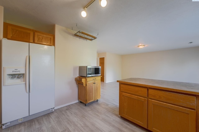 927 N Owen Ave, Pasco, WA 99301 - kitchen featuring white fridge with ice dispenser, stainless steel microwave, light wood-style flooring, brown cabinets, and baseboards