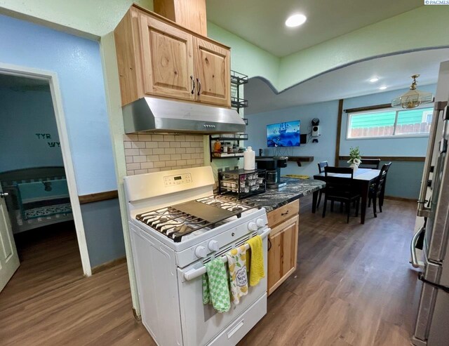 2402 Dover St, Richland, WA 99352 - kitchen with white gas range, under cabinet range hood, dark wood-style flooring, light brown cabinets, and decorative backsplash
