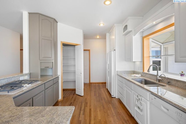1815 NW Nicole Ct, Pullman, WA 99163 - kitchen featuring a sink, white appliances, light wood-style floors, light stone counters, and glass insert cabinets