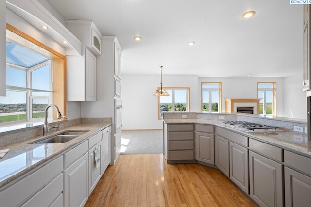 1815 NW Nicole Ct, Pullman, WA 99163 - kitchen with a sink, white appliances, a fireplace, a peninsula, and white cabinetry