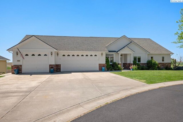 1815 NW Nicole Ct, Pullman, WA 99163 - view of front of home with an attached garage, concrete driveway, a front lawn, and brick siding