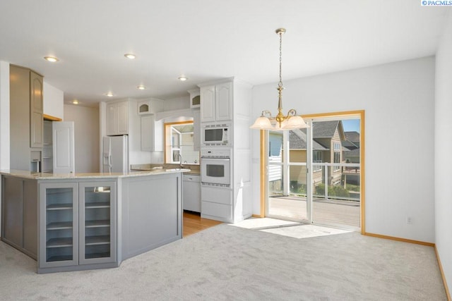 1815 NW Nicole Ct, Pullman, WA 99163 - kitchen featuring white appliances, light colored carpet, glass insert cabinets, a chandelier, and hanging light fixtures