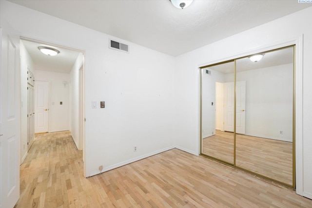 unfurnished bedroom featuring light hardwood / wood-style floors and a closet