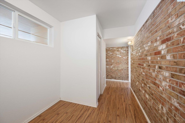 hallway featuring brick wall and hardwood / wood-style floors