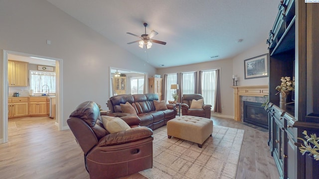 living room with a healthy amount of sunlight, sink, a fireplace, and light wood-type flooring