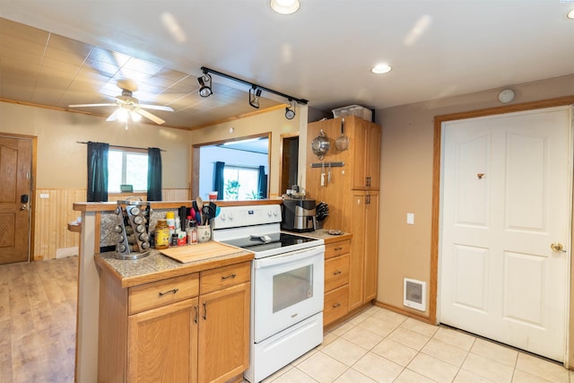kitchen featuring electric stove, ceiling fan, light countertops, wainscoting, and a peninsula