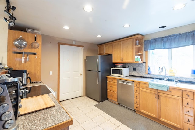 kitchen featuring stainless steel appliances, a sink, decorative backsplash, light tile patterned flooring, and open shelves