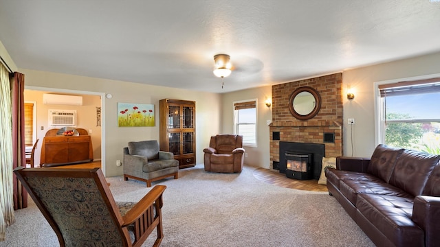 living area featuring an AC wall unit, a fireplace, a wall unit AC, and light carpet