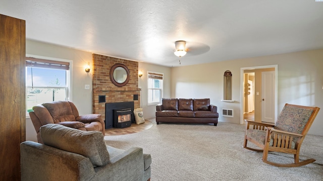 carpeted living area featuring visible vents, ceiling fan, and a fireplace