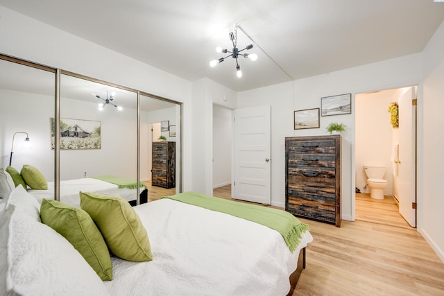 bedroom with ensuite bathroom, a notable chandelier, baseboards, a closet, and light wood-type flooring