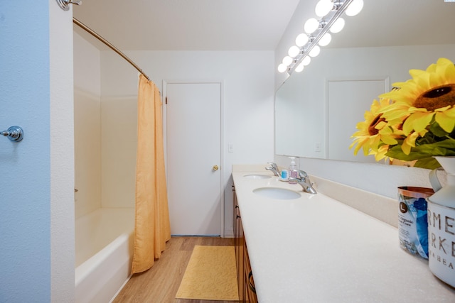 full bathroom with double vanity, shower / bath combo with shower curtain, a sink, and wood finished floors